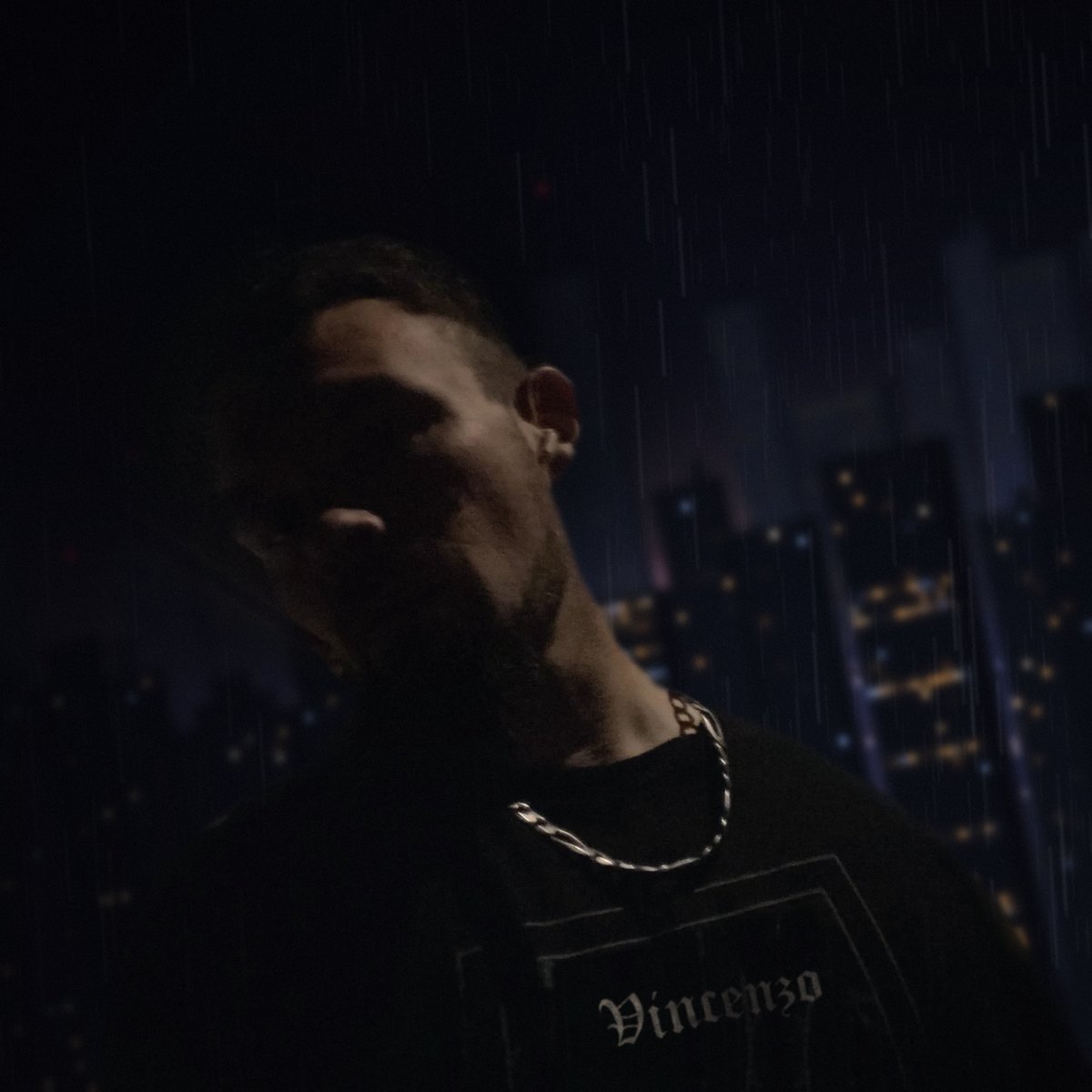 Vincenzo Scarlione at night in the rain, city lights behind him